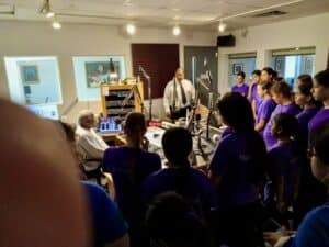 GEM students in a WDNA radio studio observing mentors at work, learning about broadcasting and media careers.