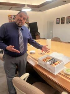 Russell Otway pointing at Holy Crab Delivery stone crab box during voiceover campaign photoshoot inside conference room.